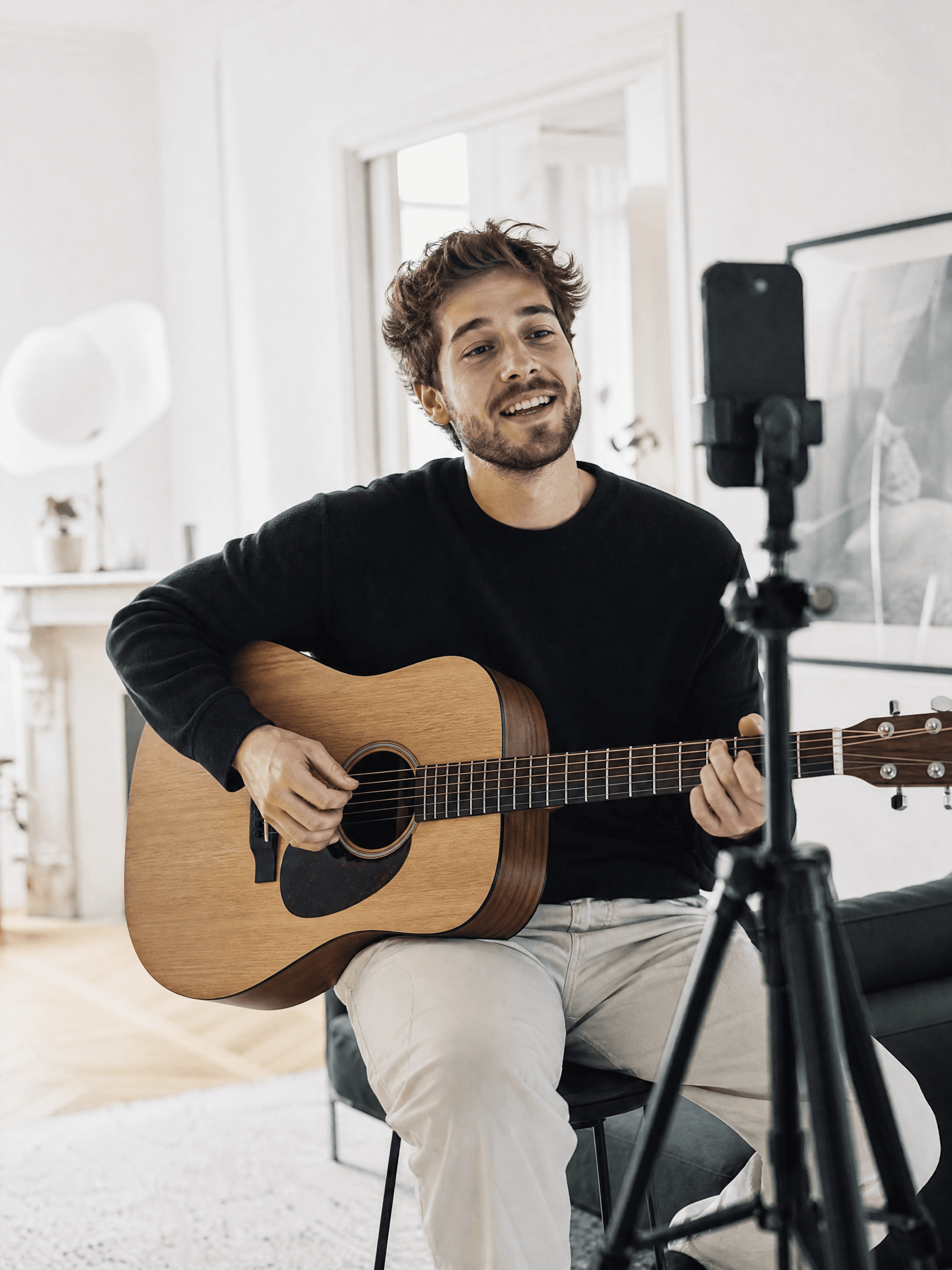 Musicien qui joue de la guitare face à son téléphone