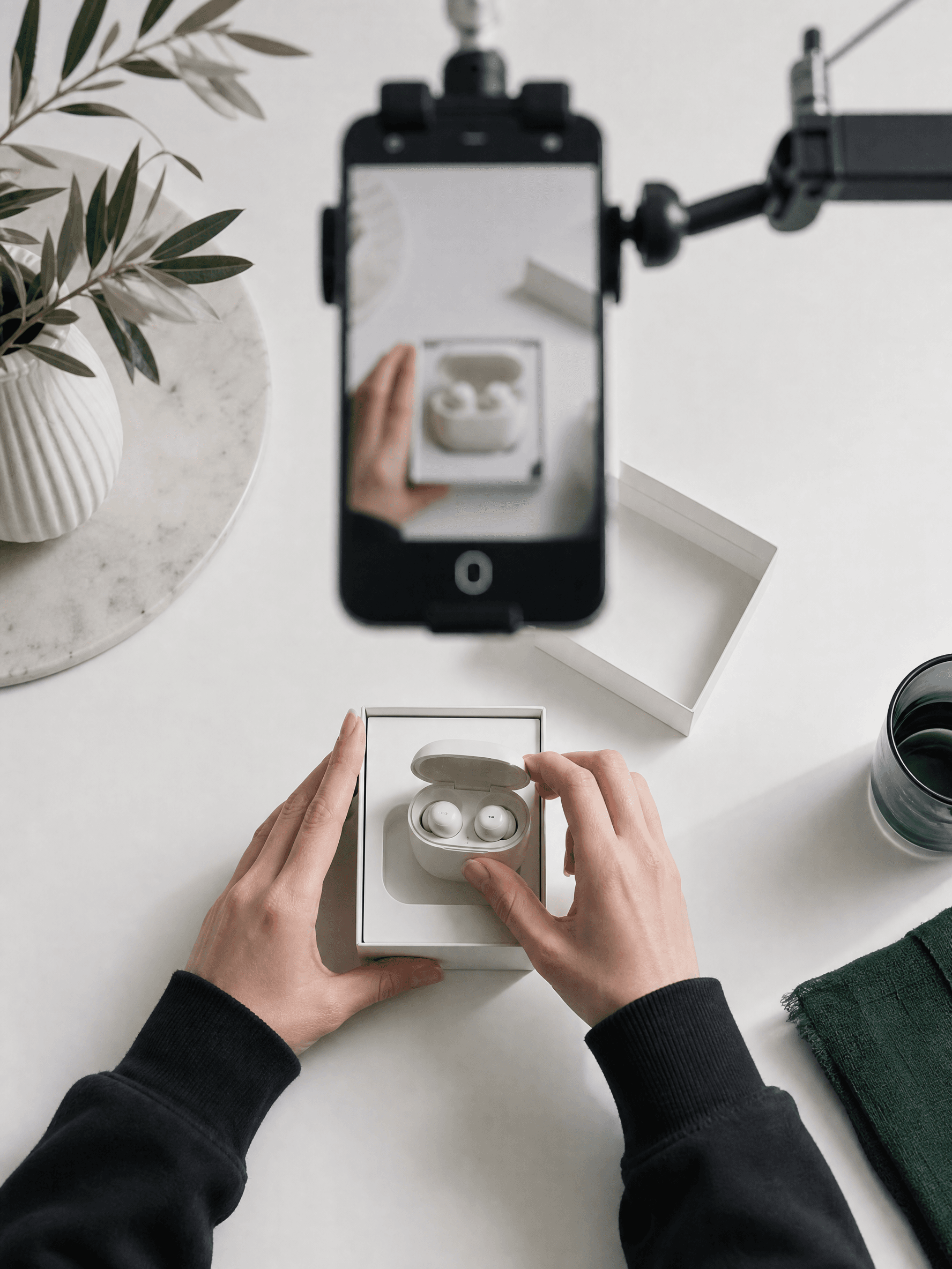 Mains qui déballent des écouteurs sous l'œil d'un téléphone